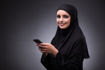 Muslim woman in black dress against dark background