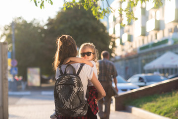 Hipster style mother and daughter walks in city street