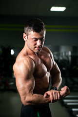 Fototapeta na wymiar Male athlete or bodybuilder shows his muscles before a workout in the gym