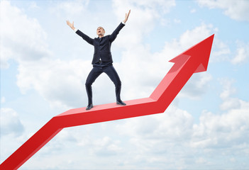 Fototapeta premium Businessman expressing happy and standing on big red line graph with an upturned arrow