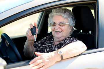 happy cheerful elderly senior woman driving and showing her new car key