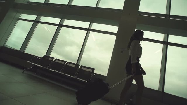 Woman in heels goes at airport and roll suitcase on wheels. in slow motion