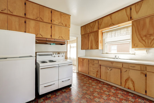 Interior Of Old Fashioned Kitchen Room With Linoleum Floor , Wooden Cabinets And White Refrigerator And Stove. Northwest, USA