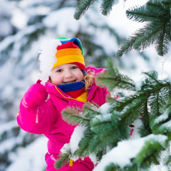 Little girl with icicle in snowy winter park