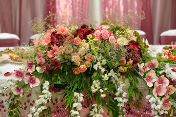 Beautiful white wedding arch decorated with pink and red flowers outdoors