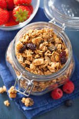 homemade healthy granola in glass jar and berries