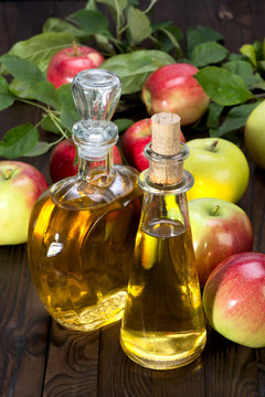 apple cider vinegar in a glass vessel and apples