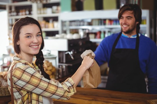 Woman Receiving Parcel From Waiter At Counter