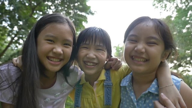 Slow motion shot : Group of little happy Asian girls playing together in the park