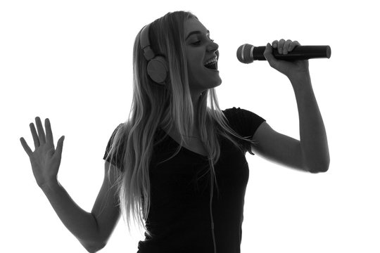 silhouette of a beautiful woman in headphones and with a microphone