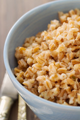 boiled cereals in blue bowl on brown wooden background