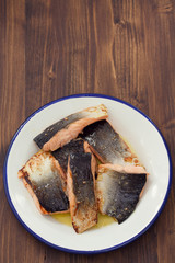 fried salmon on white dish on wooden background