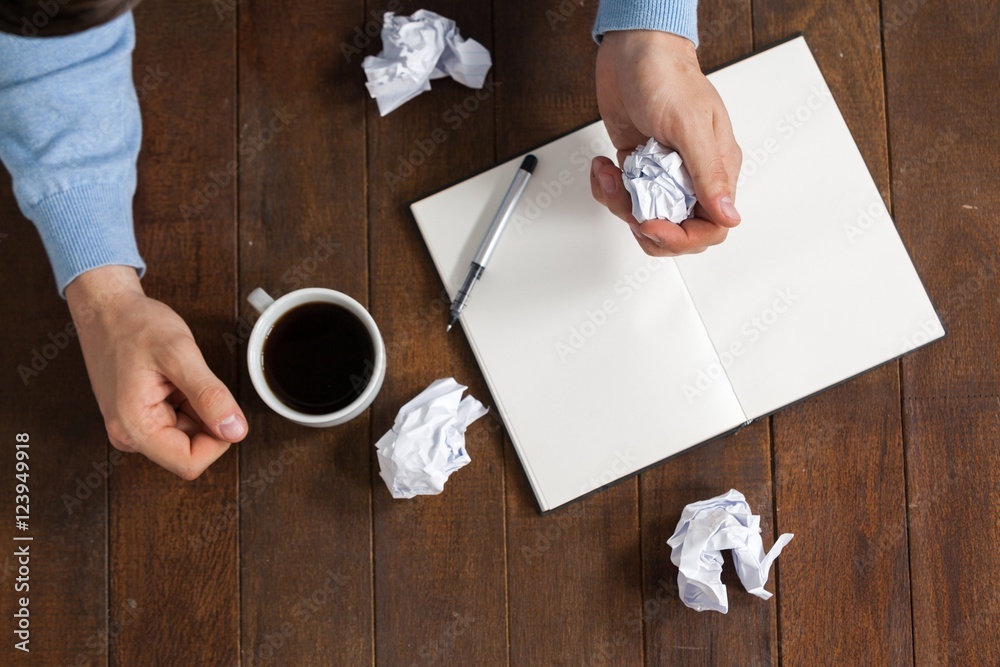 Poster man crumpling paper while having cup of coffee