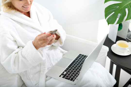 Mature lady with modern gadgets at spa