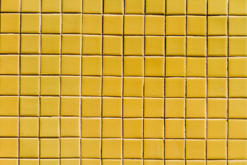 A wall surface with small yellow tiles