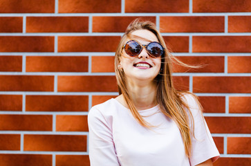 Young elegant woman in sunglasses front of brick wall backround