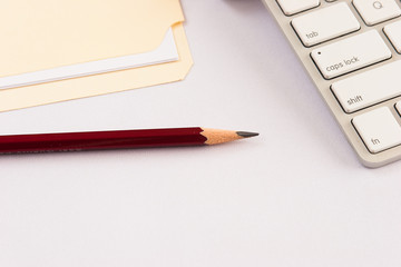 Pencil with keyboard and file folder against white background