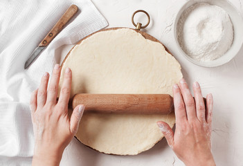 Women's hands roll the dough