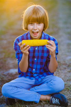 Happy boy eating healthy corn on the cob