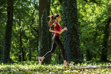 Sporty young woman running in the park and listening to music. Sport lifestyle.