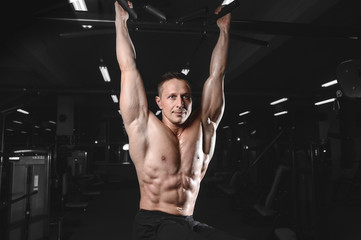 Fototapeta na wymiar Handsome athletic fitness man posing and trains in the gym.
