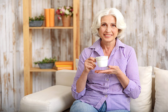 Happy Old Lady Drinking Hot Beverage At Home