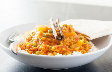 A potato, pea and lentil curry with white rice and a roti in a white bowl