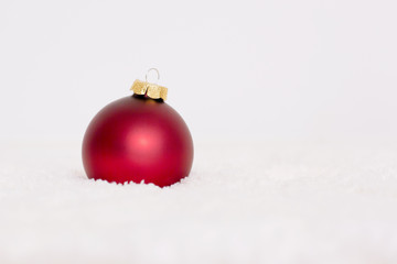 Red ball is on a white background. Glass round Christmas toy for decoration of a Christmas tree. 