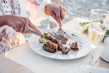 Juicy beef steak, fork and knife with woman's fingers with french manicure