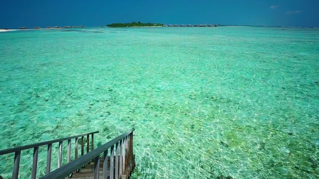 Young man snorkeling in tropical lagoon with over water bungalows on Maldives island
