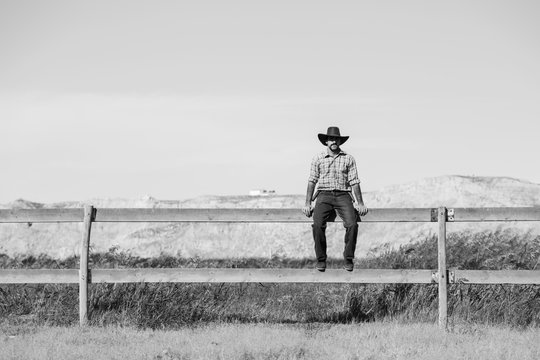 cowboy sitting on a fence