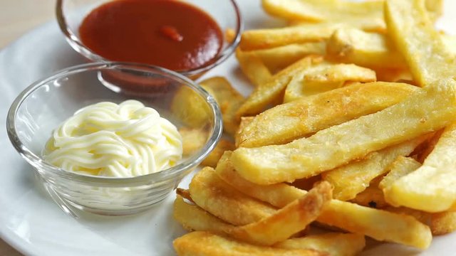 French fries with ketchup and mayonnaise. a potato chip is dipped in mayonnaise