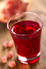 Grenadinesirup in Glas mit Granatapfel (Selektiver Fokus, Fokus auf das vordere Glasrand)