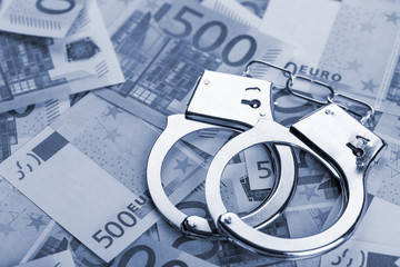 Pair of handcuffs closeup on euro banknotes background