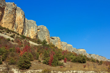 Fototapeta na wymiar Rock, a mountain range in the background of blue cloudless sky.