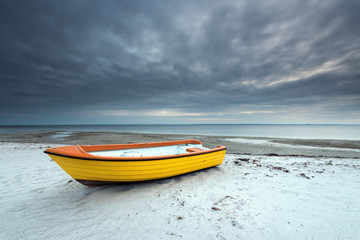 Alone boat on the sandy beach in cloudy day. Baltic Sea. Poland.