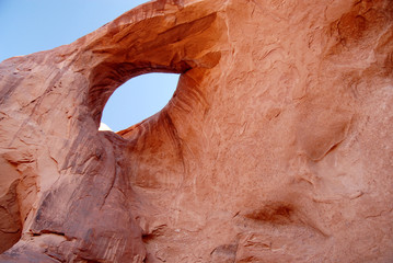 Eye of the Sun natural sandstone arch,. A great perfectly formed blue eye (the sky shown through), rimmed with black eye-lashes in Monument Valley Navajo Tribal 