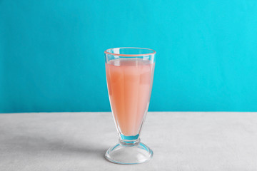 Glass of pink lemonade on white table and blue background