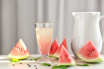 Homemade refreshing drink in glass and watermelon slices on table