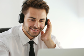 Handsome young man listening to music with headphones and working on laptop at office