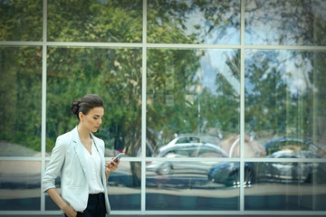 Beautiful businesswoman with phone on window background