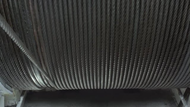 Big winch drum with metal rope on it rotating