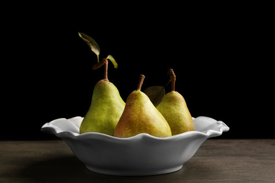 Green pears in plate on black background