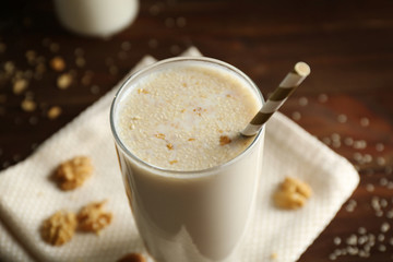 Delicious milkshake with nuts on wooden background