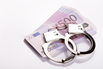 Pair of handcuffs closeup on euro banknotes stack