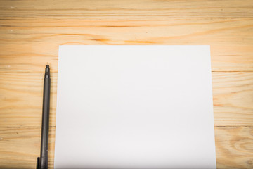 Blank white paper with pen on a wooden desk.