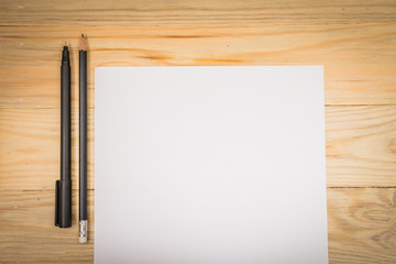 Blank white paper with pen on a wooden desk.