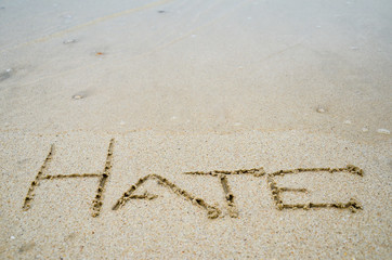 Abstract sign of word hate written on a sand beach background