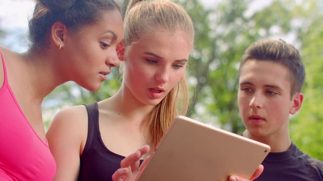 Friends looking tablet. Shocked faces. Surprised people. Young people tablet. Multiracial people outdoor. Shocking news. Multicultural students using tablet computer. Friends tablet. Shock