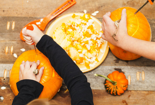 Close-up Kids Hands Carving Halloween Pumpkins